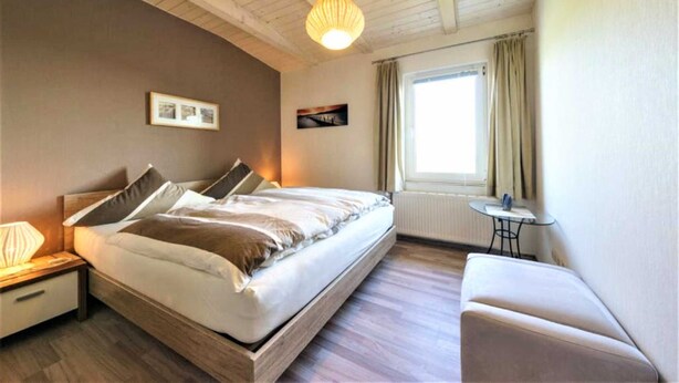 Une chambre à coucher comprenant un lit, une table de chevet, une lampe et une petite table avec une chaise.