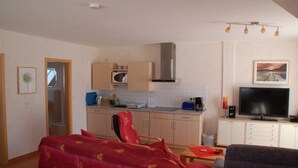A compact living space with a kitchenette, a dining area, and a seating area. - Apartment Anna - House Uhleck (Lohme)