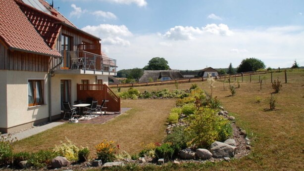 A two-story house with a balcony, a patio with outdoor furniture, and a well-maintained garden. - Apartment Anna - House Uhleck (Lohme)