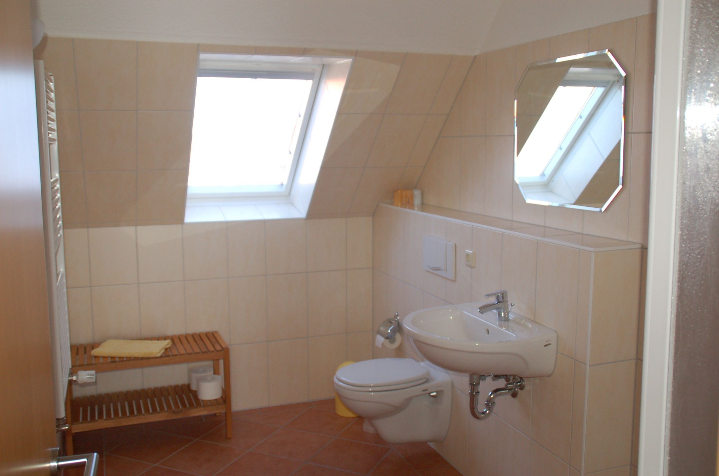 Une petite salle de bain avec un puits de lumière, des toilettes, un lavabo et une étagère en bois.