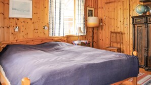 Une pièce en bois contenant un lit, une lampe, un globe terrestre et un meuble.