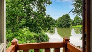 A view from a wooden balcony overlooking a calm river surrounded by lush greenery. - 5 bedroom awesome home in Luche Pringe (Luche Pringe)