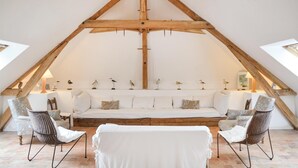 A cozy attic room with a sloped ceiling, a white sofa, wicker chairs, and bird sculptures on the wall. - 5 bedroom awesome home in Luche Pringe (Luche Pringe)