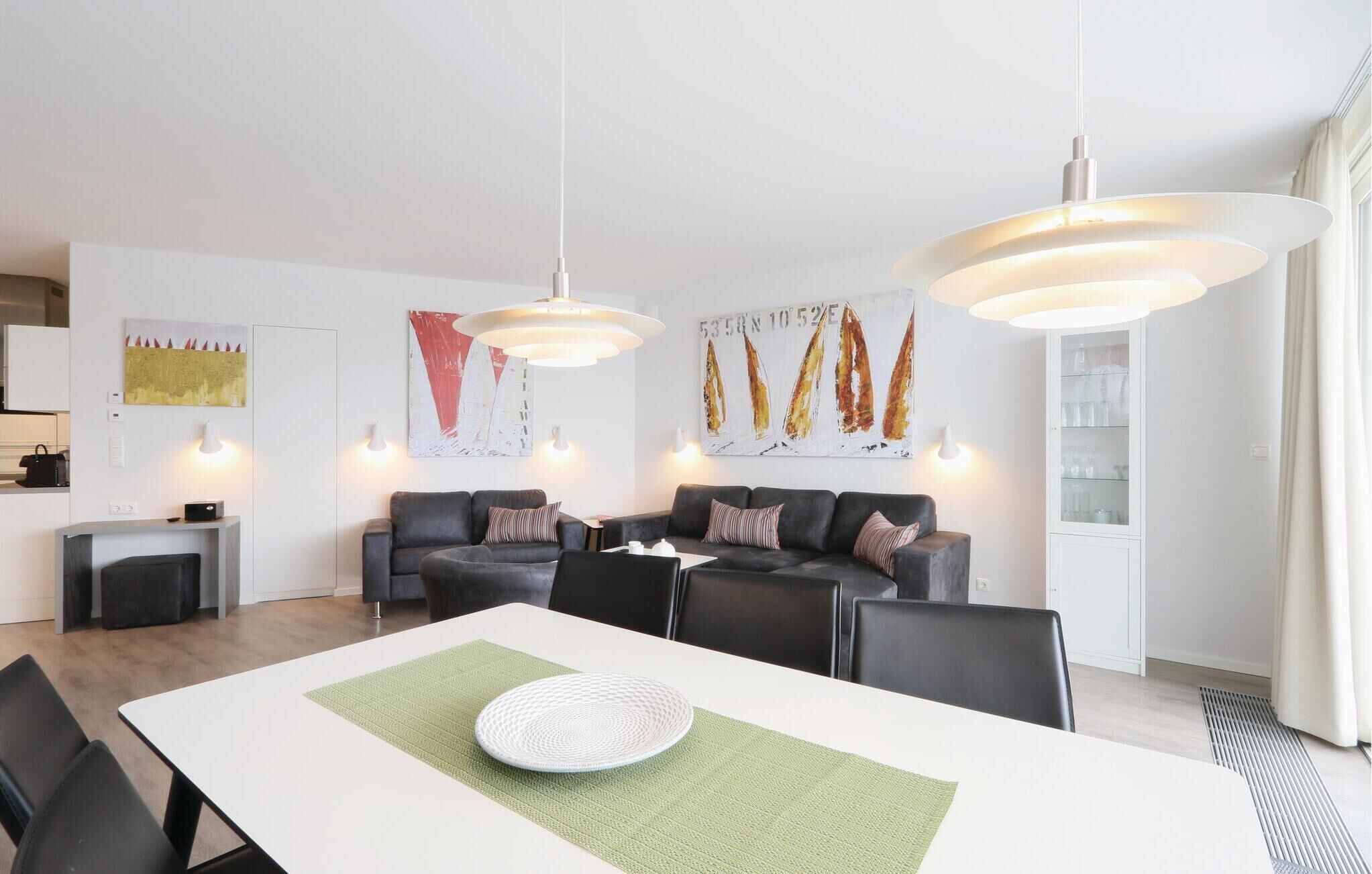 En moderne stue med spiseplads, der inkluderer en sofasæt, et spisebord med en grøn pladsedug og kunst på væggene.