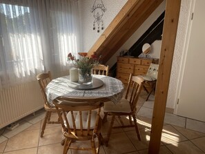 Ein Essbereich mit einem runden Tisch, Holzstühlen und einer Blumenvase.