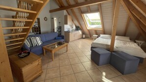 Ett mysigt sovrum på vinden med en trappa i loftstil, en soffa, en säng och ett litet köksutrymme.
