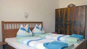 A bedroom with a wooden bed, pillows, a blanket, and a wardrobe. - Große Ferienwohnung Sierndorf (Sierndorf)
