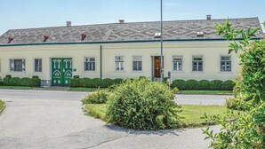 A two-story building with a green door and windows, surrounded by well-maintained hedges and a clear sky. - Große Ferienwohnung Sierndorf (Sierndorf)