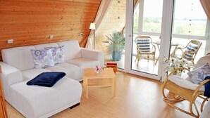 Une pièce chaleureuse avec un canapé blanc, une petite table en bois et des chaises en osier.