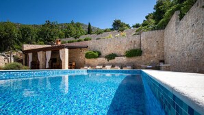 A swimming pool with stone walls, a covered seating area, and a view of a hillside. - 6 bedroom accommodation in Klek (Klek)