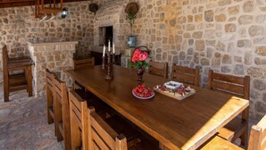 A stone-walled dining area with a wooden table set for four, candles, and a basket of flowers. - 6 bedroom accommodation in Klek (Klek)