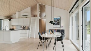 A modern kitchen with white cabinets, a central island, and a dining area with a round table and chairs. - Beach front home in Fjerritslev with WiFi (Fjerritslev)