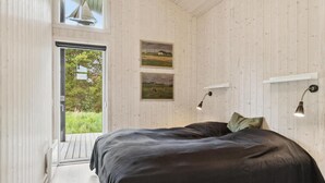 A bedroom with a large bed, wooden walls, and a view of greenery outside. - Beach front home in Fjerritslev with WiFi (Fjerritslev)