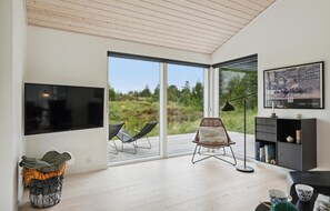 Relax in this cozy living space with a flat-screen TV, wicker chair, and bookshelf.