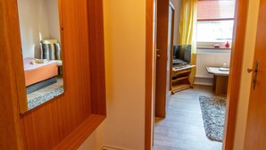 Une chambre à coucher avec un lit, une armoire, un miroir et une fenêtre avec des rideaux.