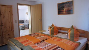 A bedroom with a wooden bed, two pillows, a nightstand, and a painting on the wall. - Vacation home Lorenz - Apartment 1/EG (Mölschow)