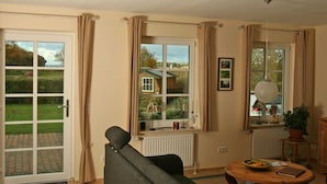En stue med en sofa, et bord med frugt i en skål og et vindue med gardiner.