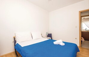A hotel room with a bed, a nightstand, a chair, and a mirror.