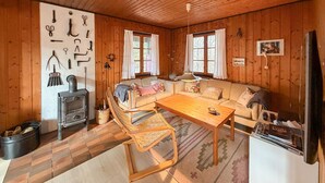 Ein gemütliches Blockhauszimmer mit einer Couch, einem Holztisch und einem Kamin.
