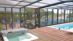 Un espace extérieur abrité comprenant un jacuzzi, une piscine et un jardin agrémenté de fleurs et de plantes.