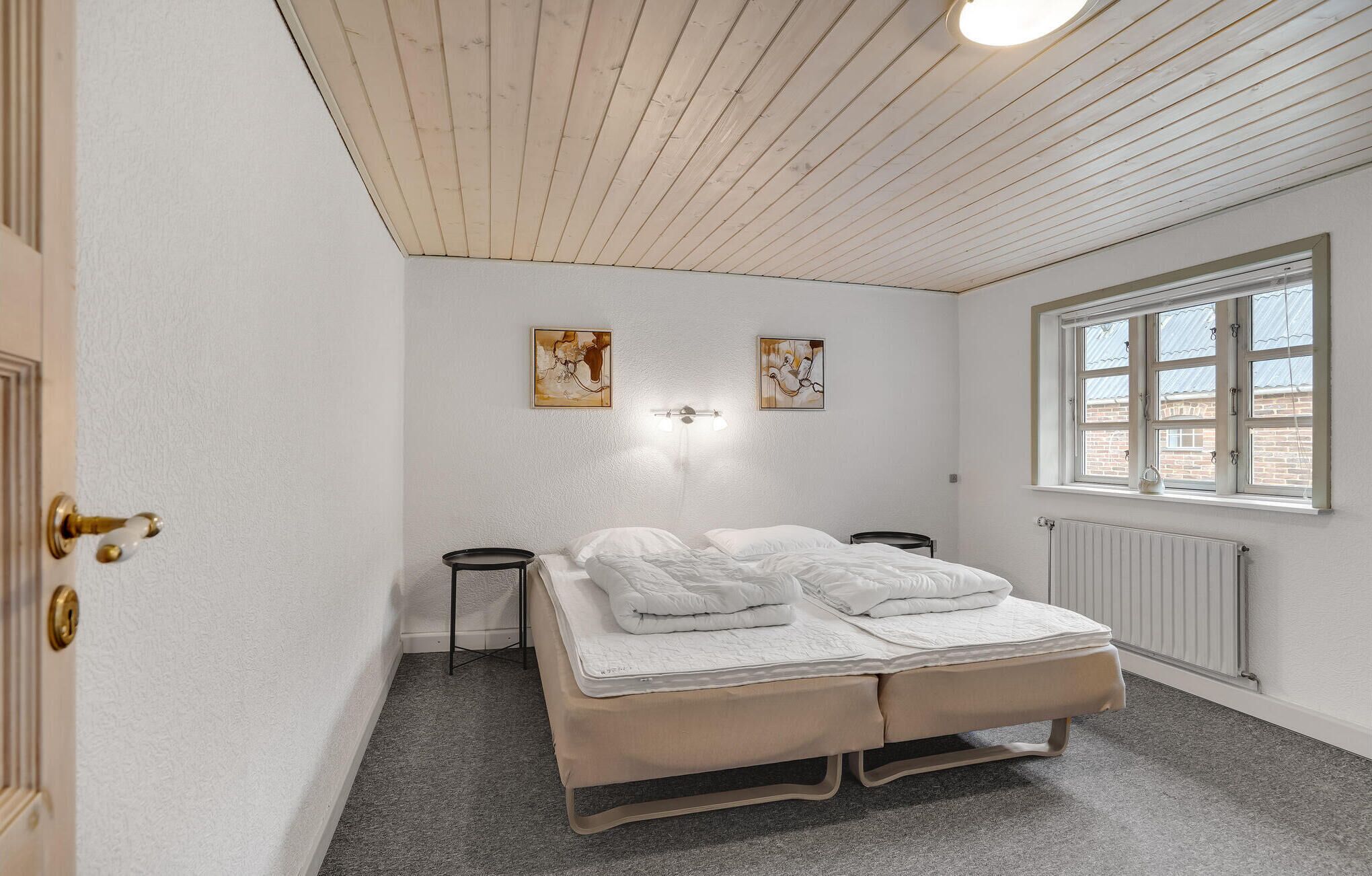 Une chambre à coucher comprenant un lit, une fenêtre et deux œuvres d’art accrochées au mur.