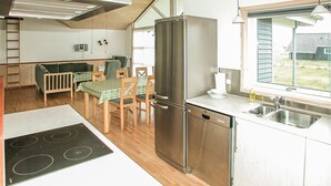 A compact kitchen with a stainless steel refrigerator, wooden dining table, and chairs. - Lovely home in Tarm with sauna (Tarm)