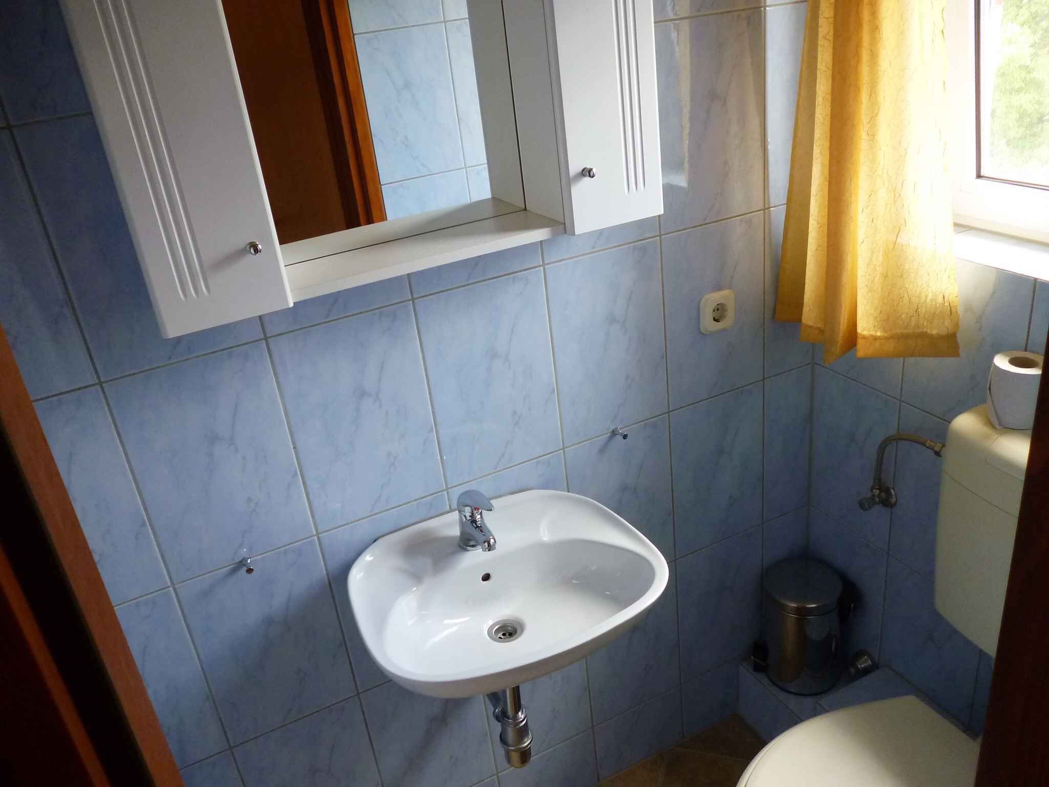 A bathroom with a white sink, a mirror above it, and a toilet.