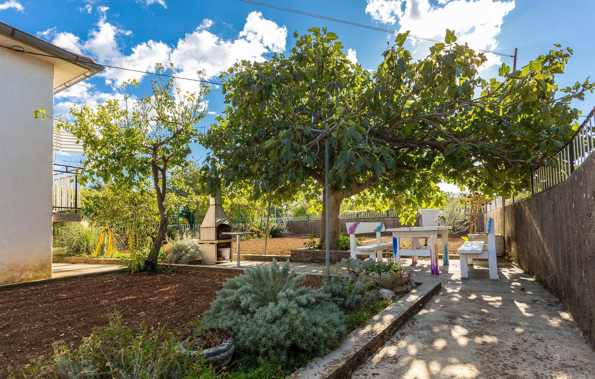 A garden with a barbecue area, a small table, and a bench.