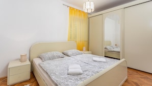 A bedroom with a bed, bedside table, lamp, and a mirror.