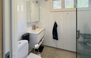 A bathroom with a toilet, sink, mirror, and towel rack. - 4 bedroom amazing home in Erfjord (Erfjord)