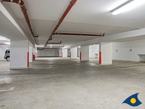 An empty parking garage with white walls, numbered parking spaces, and visible red pillars.