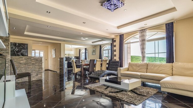 A spacious living area with a modern sofa, a coffee table, and a dining area with chairs.