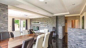 A modern dining area with a wooden table and chairs, a TV, and stone accents on the walls.