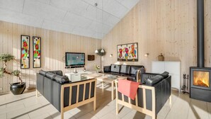 Uma sala de estar moderna com lareira, paredes de madeira, um sofá, uma mesa de centro e obras de arte.