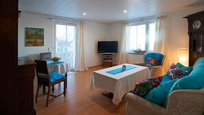 Uma sala de estar com sofá, televisão, mesa e uma cadeira.
