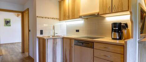 A modern kitchen with wooden cabinets, a dishwasher, and a coffee maker.