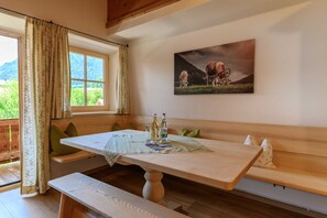 Ein Zimmer mit einer hölzernen Bank, einem Tisch mit Tischdecke, Flaschen und einem Bild von Kühen an der Wand.