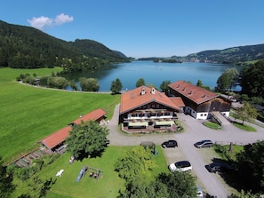 Un hotel junto al lago con un edificio grande, un estacionamiento y un parque infantil.