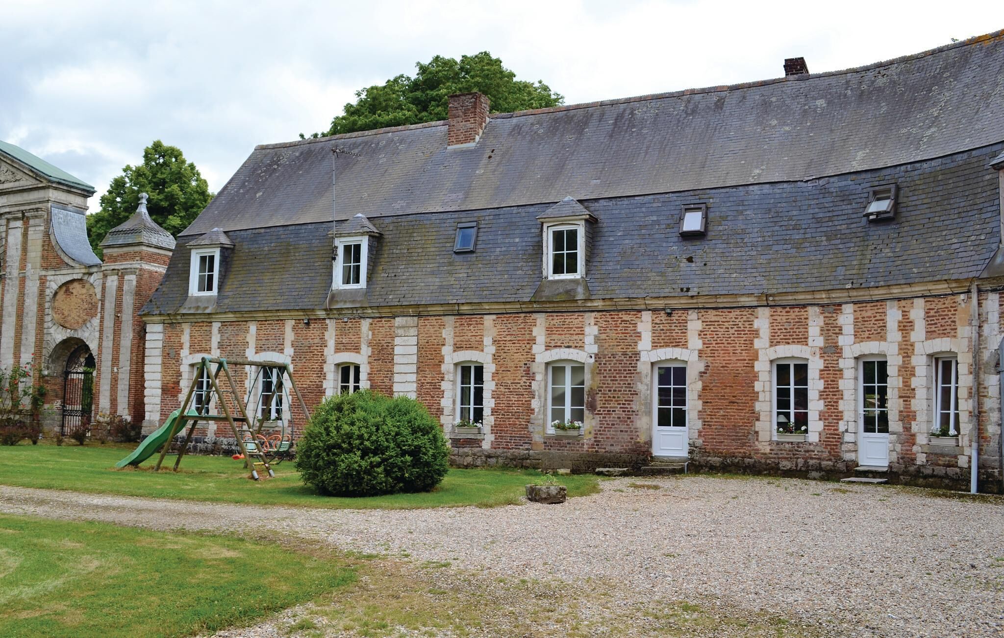 Een historisch gebouw met een symmetrische gevel, meerdere ramen en een kiezelhof.