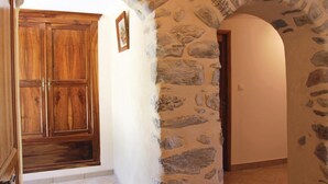 A stone-walled hallway with a wooden door and a framed picture on the wall. - 2 bedroom gorgeous home in Sigoyer (Sigoyer)