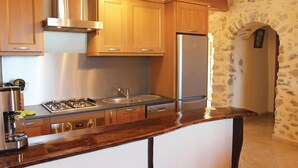 A kitchen with wooden cabinets, stainless steel appliances, and a stone wall. - 2 bedroom gorgeous home in Sigoyer (Sigoyer)