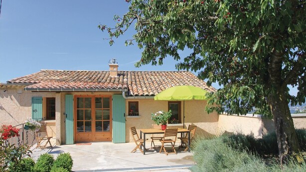 A house with a tiled roof, a patio with a table and chairs, and a green umbrella. - 2 bedroom gorgeous home in Sigoyer (Sigoyer)