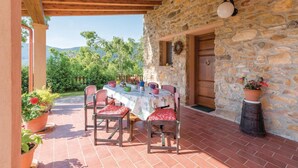 A covered outdoor dining area with a stone wall, wooden ceiling, and a view of greenery and hills. - Stunning apartment in Buti (PI) with swimming pool (Buti (PI))