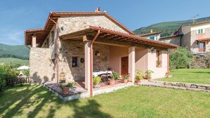 A stone house with a covered patio, a small garden, and a view of the surrounding hills. - Stunning apartment in Buti (PI) with swimming pool (Buti (PI))