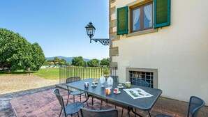 An outdoor patio with a table set for tea, surrounded by chairs, and a view of a mountain range. - Awesome apartment in Poppi AR with house a panoramic view (Poppi AR)