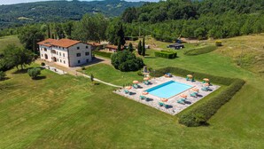 An aerial view of a property with a swimming pool, lounge chairs, and a large building with a red-tiled roof. - Awesome apartment in Poppi AR with house a panoramic view (Poppi AR)