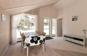A dining area with a table covered in a cow print tablecloth, surrounded by wicker chairs. - 3 bedroom awesome home in Nexø (Nexø)