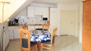 A compact kitchen with white cabinets, a microwave, and a dining table with chairs. - Apartment 2.4 - 55sqm with fireplace and 2 bedrooms - ADS apartments **approx. 20 (Ückeritz)