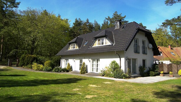 A two-story house with a sloped roof, a chimney, and a well-maintained lawn. - Apartment 2.4 - 55sqm with fireplace and 2 bedrooms - ADS apartments **approx. 20 (Ückeritz)