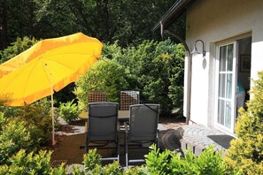 A patio with a yellow umbrella, two chairs, and a table.